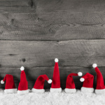 Weihnachtlicher Hintergrund Holz grau mit Weihnachtsmützen rot